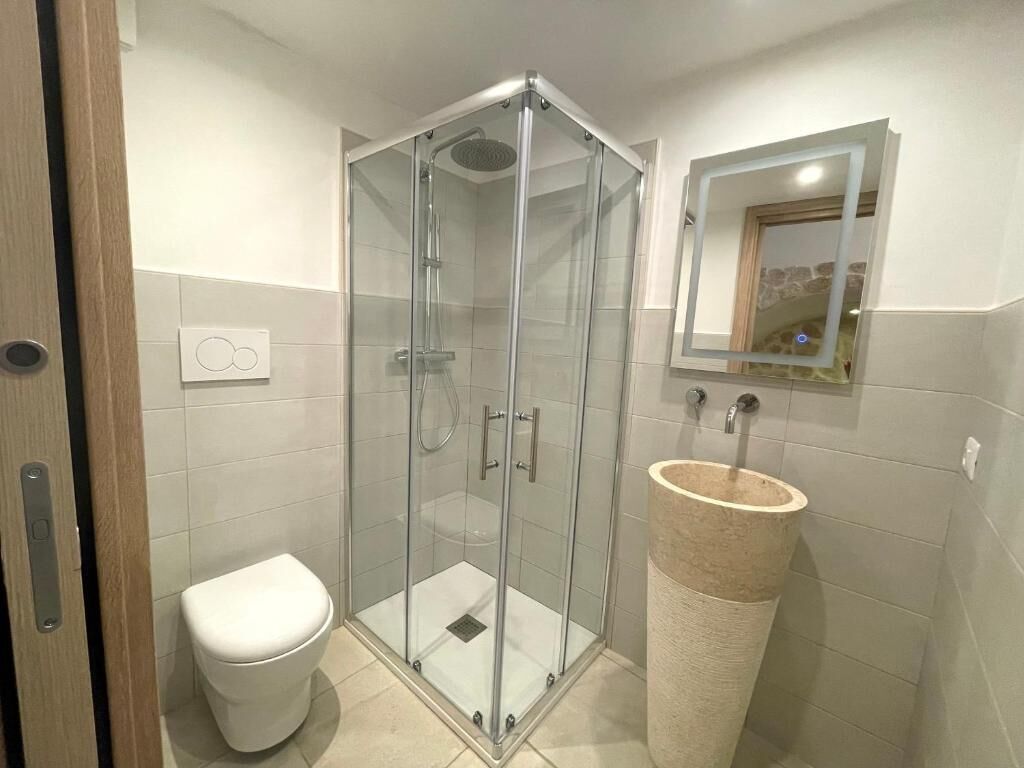 Ein Badezimmer mit einer Duschkabine, einer Toilette und einem Waschbecken mit Steinbecken.