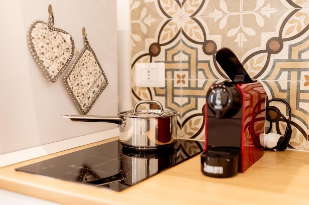 Une cuisine équipée d’une cuisinière moderne, d’une bouilloire et d’une machine à café, le tout posé sur le plan de travail.