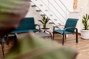 Un área de estar moderna con escaleras, piso de madera y plantas en macetas.