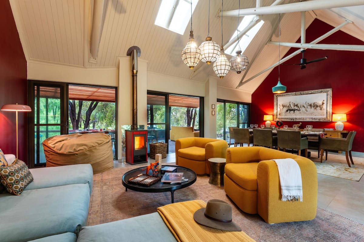 A spacious living room with a fireplace, comfortable seating, and large windows offering a view of the outdoors.