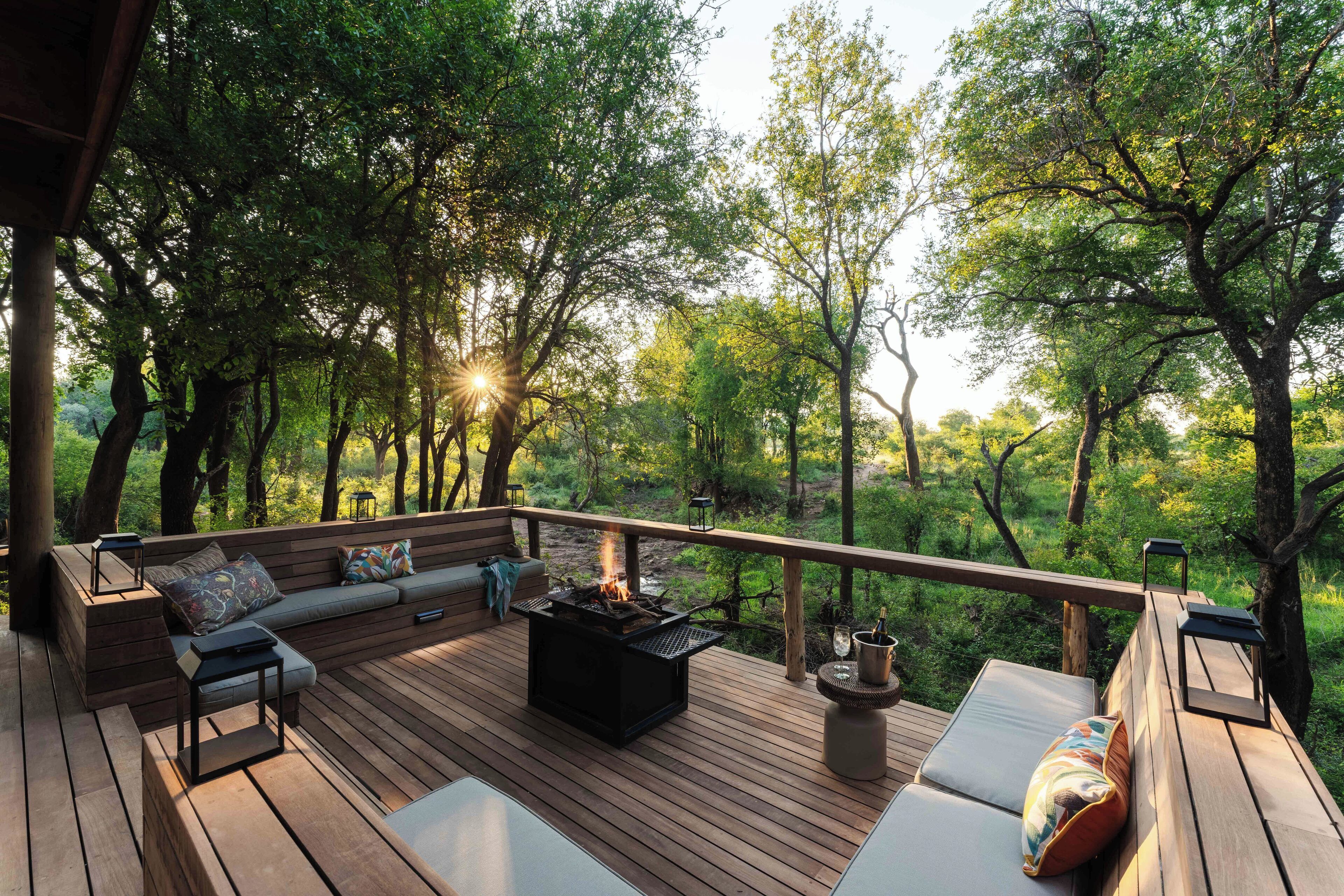 A deck with a fire pit, seating, and a view of the forest.