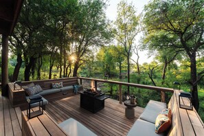 A deck with a fire pit, seating, and a view of the forest. - Jaci's Private Lodge (Madikwe Game Reserve)