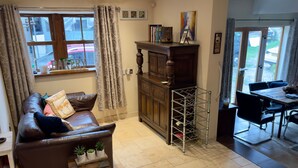 A cozy living room with a brown leather sofa, a wooden cabinet, and a dining area with a table and chairs. - Sleeps 4 - Old Farmhouse - Near Pendle Hill (Skipton)
