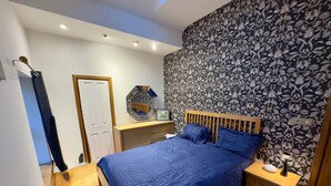 A bedroom with a wooden bed, a nightstand, a dresser, and a mirror. - Sleeps 4 - Old Farmhouse - Near Pendle Hill (Skipton)