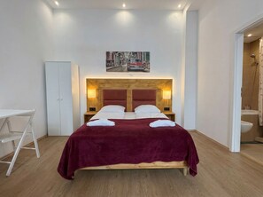 A hotel room with a bed, a desk, a wardrobe, and a bathroom. - Cozy Apartment for 3 Near Lugner City (Vienna)