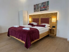 Ein Bett mit Holz-Kopfteil, zwei Nachttische, eine Wandleuchte und ein Gemälde über dem Bett.