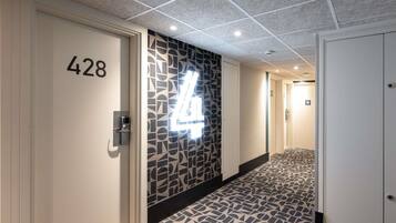 Een hotelgang met een patroon vloer, een muur met een geometrisch ontwerp, en deuren met de nummers 428 en 30.
