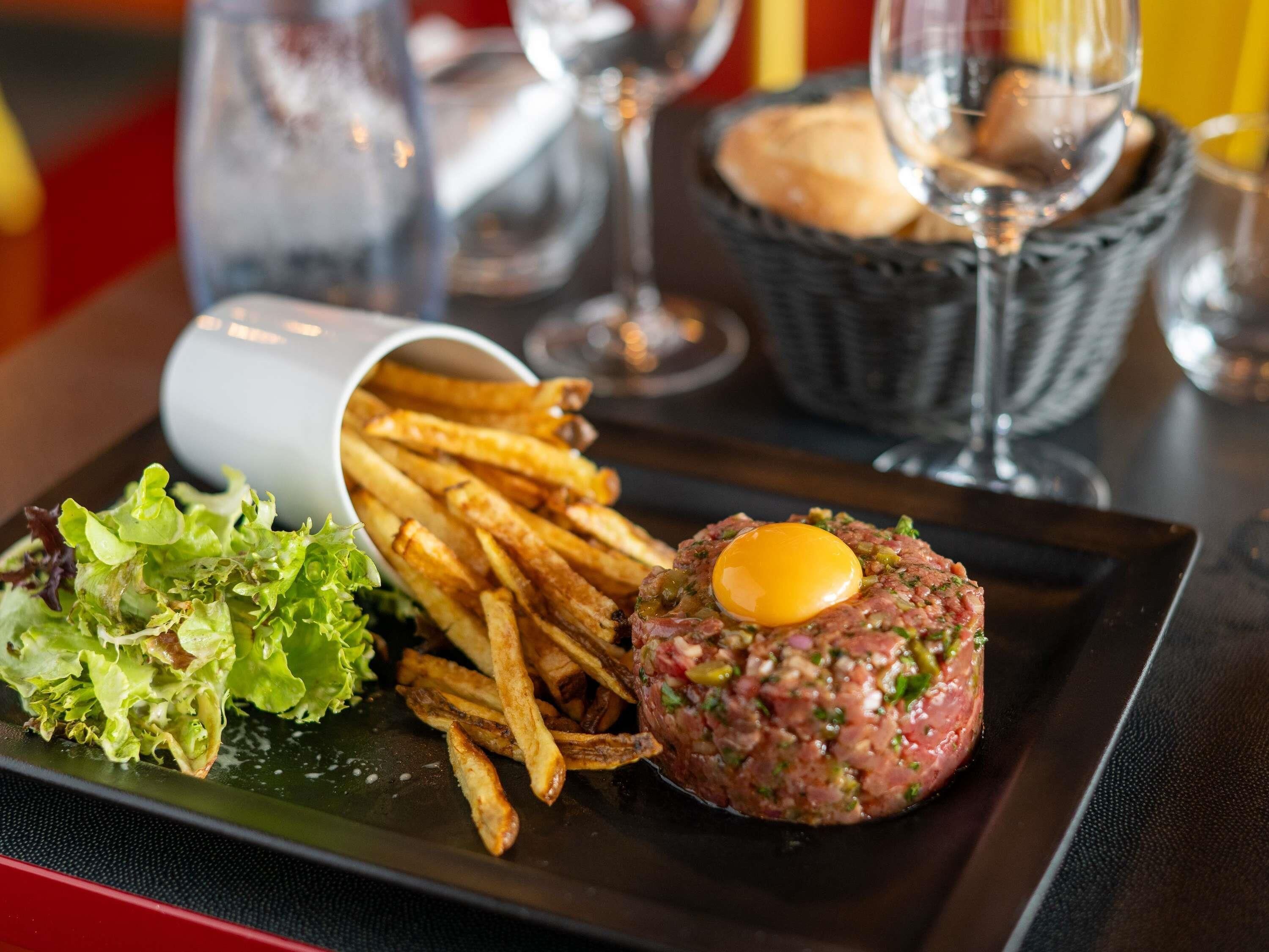 A plate with steak tartare, fries, and a salad.