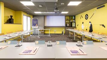 Een vergaderzaal met tafels, stoelen, een projectiescherm en een presentatiebord.