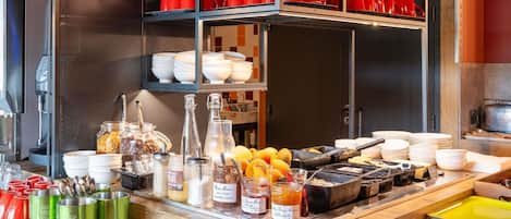 Montaje de bufé con diferentes alimentos, utensilios y recipientes.