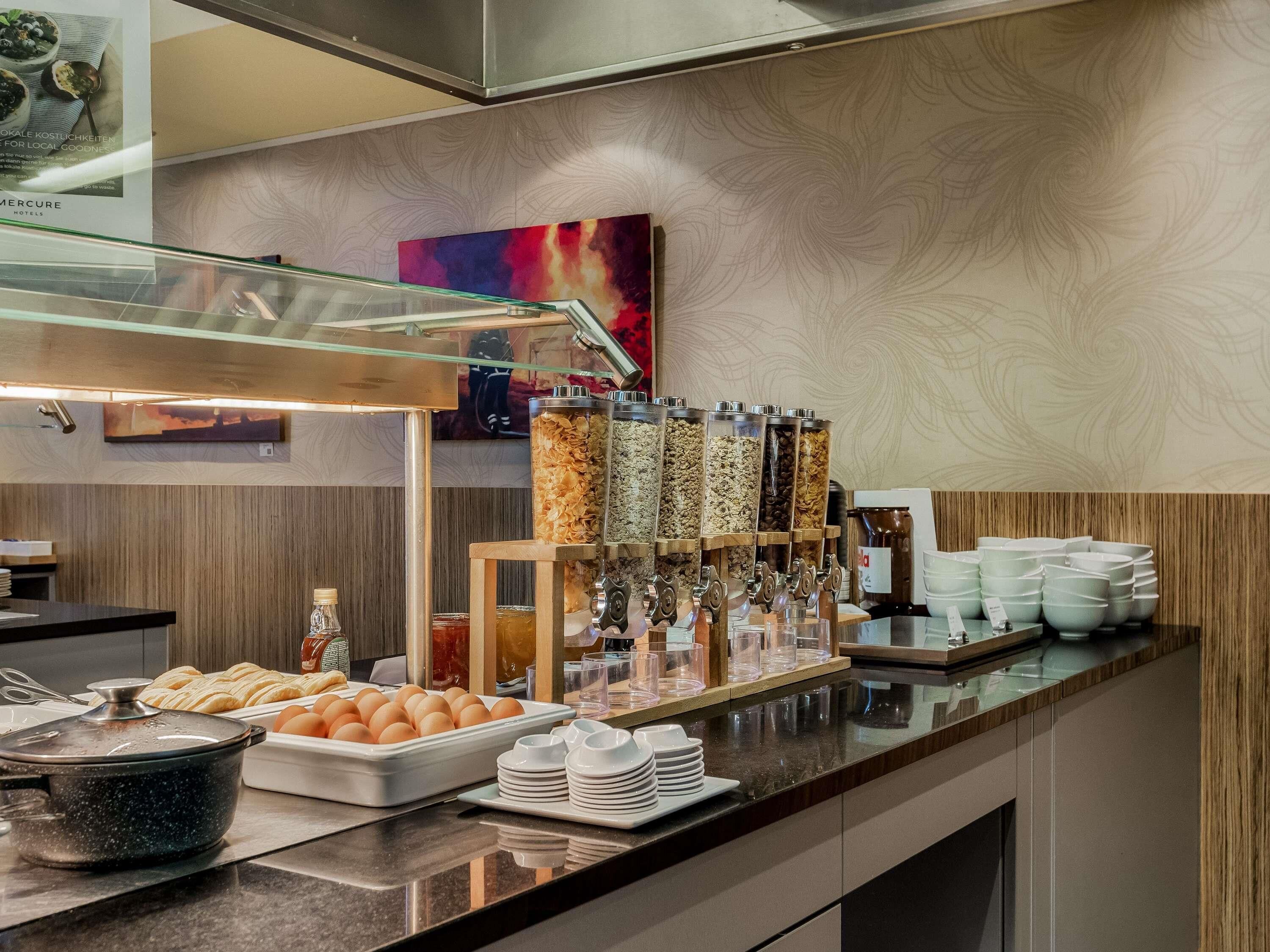 A buffet setup with various food items, a coffee station, and a glass display case.