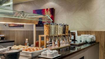 A buffet setup with various food items, a coffee station, and a glass display case.