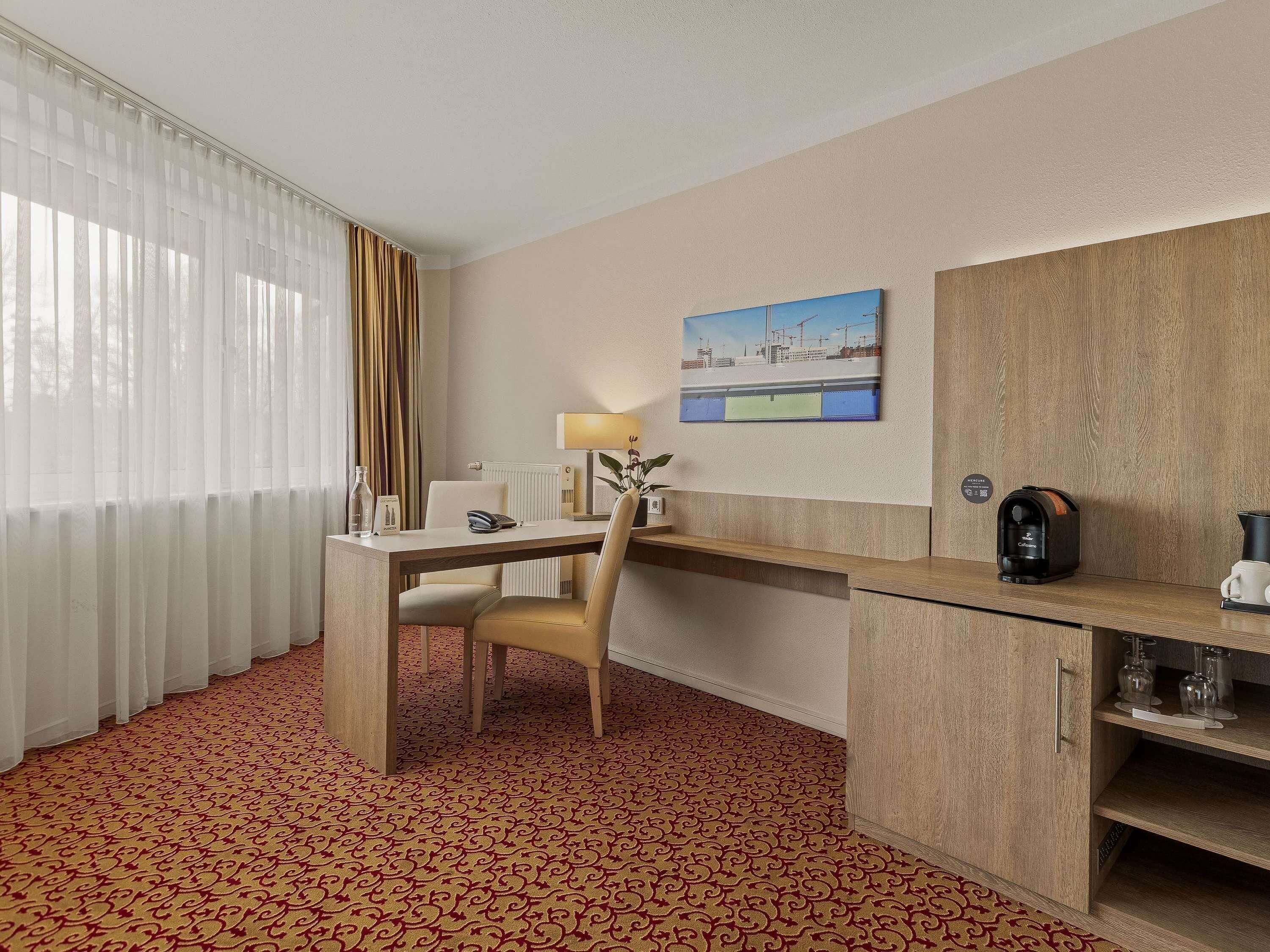 Habitación de hotel con escritorio, silla y cafetera.