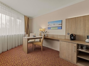 Une chambre dâhĂŽtel Ă©quipĂ©e dâun bureau, dâune chaise et dâune machine Ă cafĂ©.