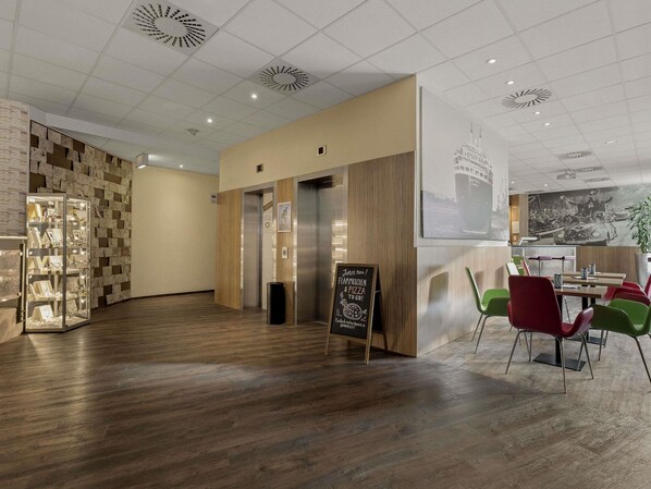 A modern interior with a wooden floor, a glass display case, and a signboard. - Mercure Hotel Hamburg Am Volkspark (Hamburg)