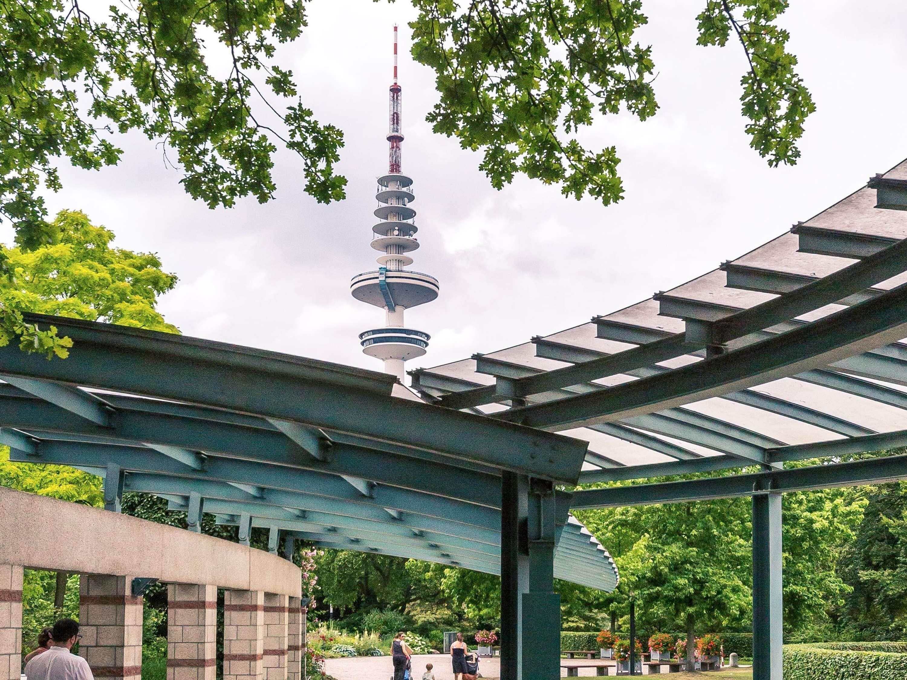 Ein überdachter Außenbereich mit Glasdach, einem Turm und Grünpflanzen.