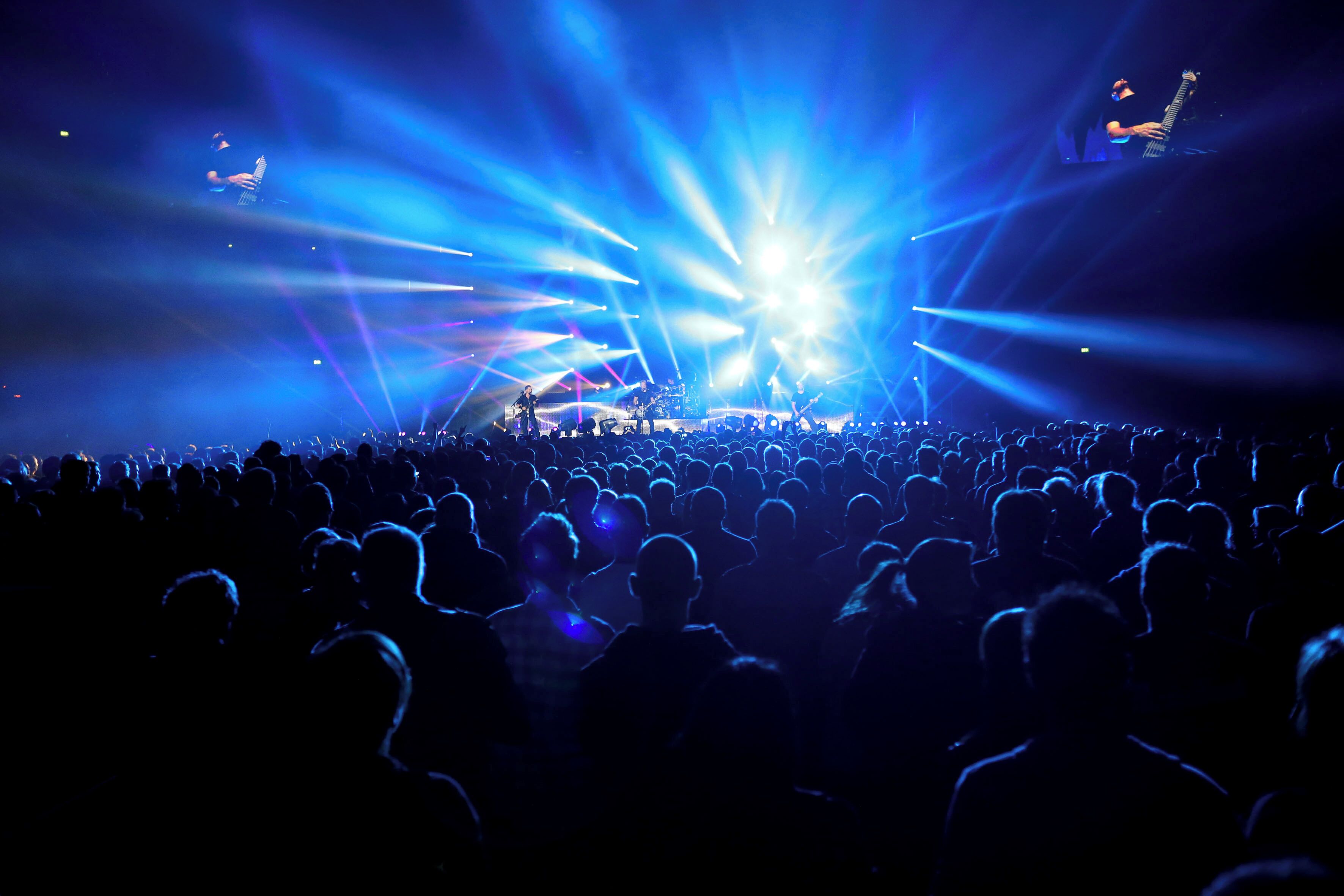 A concert with a crowd facing a stage with bright stage lights.