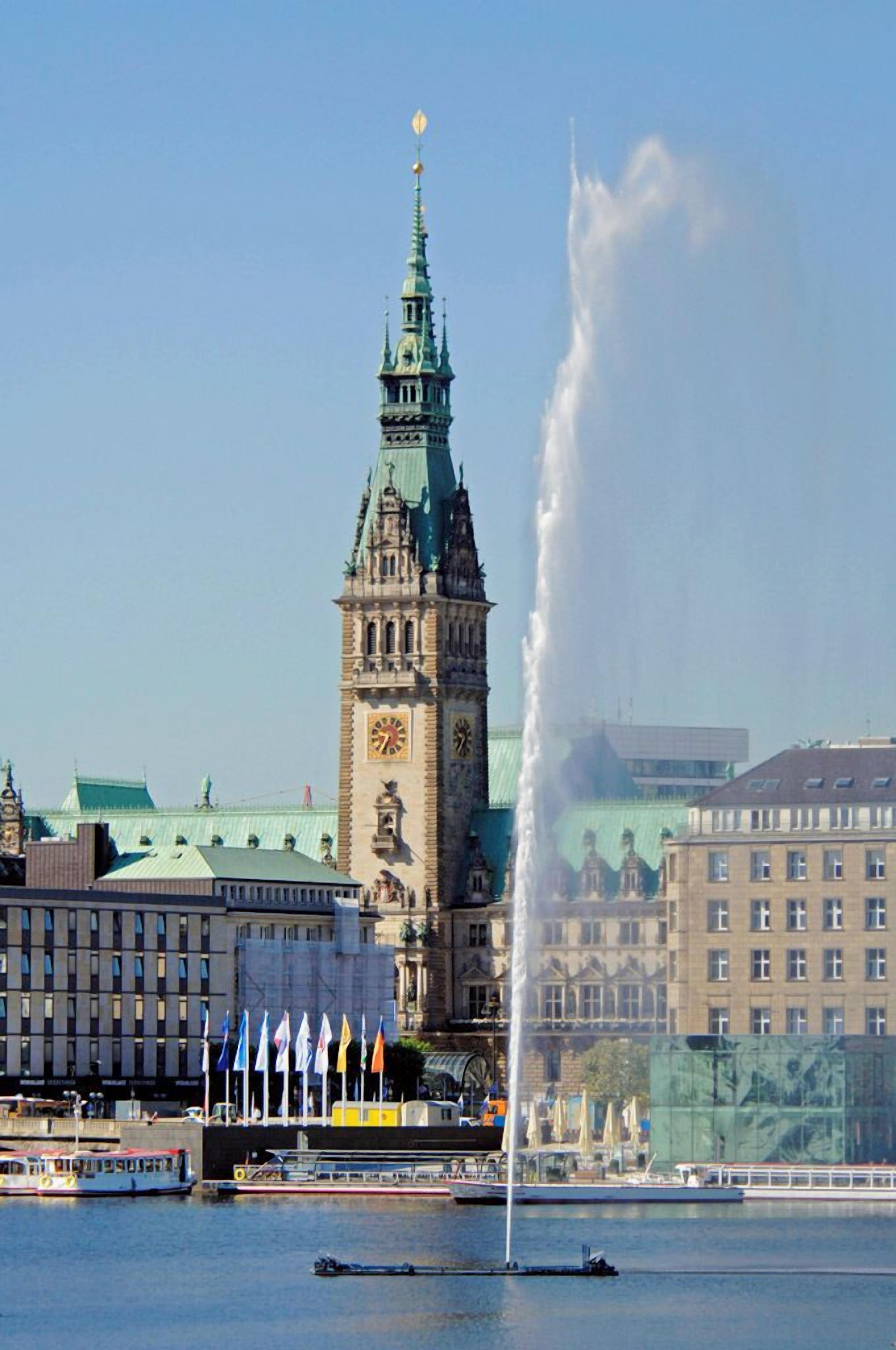 Ein historischer Turm mit einer Uhr, einem Brunnen und einem Fluss mit Booten.