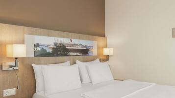 A hotel room with a bed, two wall-mounted lamps, a painting of a cruise ship, and a red chair.