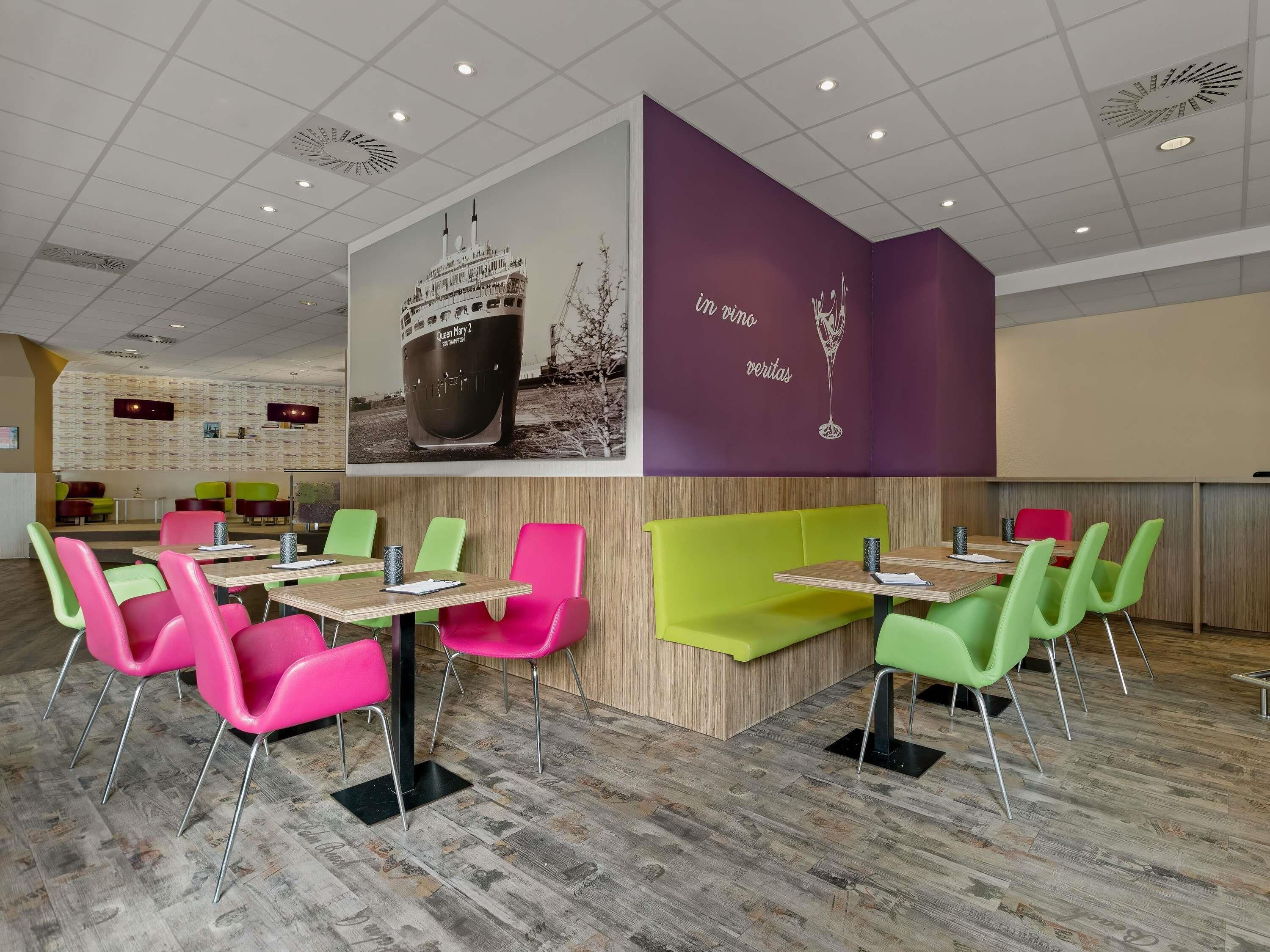 A modern restaurant with vibrant seating and a large mural on the wall.
