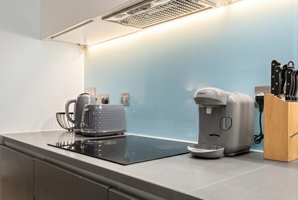A modern kitchen with an induction cooktop, a coffee maker, and a kettle. - 1-Bed Flat Sleeps 4 · Marble Bath · Walk to Monument & Bank (Greater London)