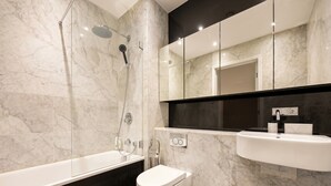 A modern bathroom with a bathtub, toilet, and a sink. - 1-Bed Flat Sleeps 4 · Marble Bath · Walk to Monument & Bank (Greater London)
