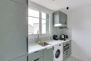 A compact kitchen with a built-in washing machine, a sink, and a window providing natural light. - Appartements rue du Maréchal Leclerc (Saint-Ouen)