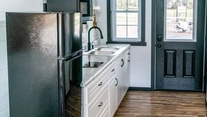 A compact kitchen with a refrigerator, sink, and wooden cabinets. - Natural Nook | Tiny Home #2 in Amish Country! (Shipshewana)