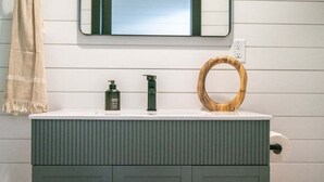 A bathroom with a white sink, two bottles of soap, a wooden ring, and a towel. - Natural Nook | Tiny Home #2 in Amish Country! (Shipshewana)