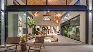 A modern interior with a central seating area, a staircase, and glass walls. - Villa Bayu by GORO (Bali)
