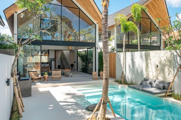 A modern house with a swimming pool, outdoor seating, and a large glass window. - Villa Bayu by GORO (Bali)