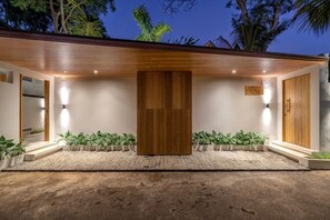 A modern building with a wooden facade, a sign reading 'Hotel', and a paved entrance area with potted plants. - Villa Bayu by GORO (Bali)