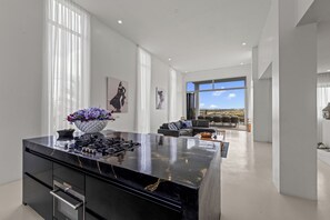 Eine moderne Küche mit Marmorarbeitsplatte, einem Einbauofen und einem großen Fenster mit Blick ins Freie.