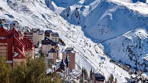 Una montaña nevada con una estación de esquí y edificios en primer plano.