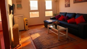 Una sala de estar con un sofá, una mesa de centro, una alfombra y dos ventanas.