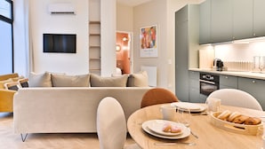 A modern living room with a sofa, a dining table with breakfast items, and a kitchen area with cabinets and appliances. - Appartements rue des Jeuneurs (Paris)