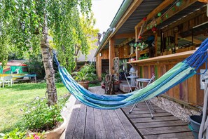 A wooden deck with a hammock, a barbecue area, and a rustic bar. - Tiny Home "Logement Bourbon - Heart of Ardèche" with Private Terrace, Shared Garden & Wi-Fi (Lamastre)