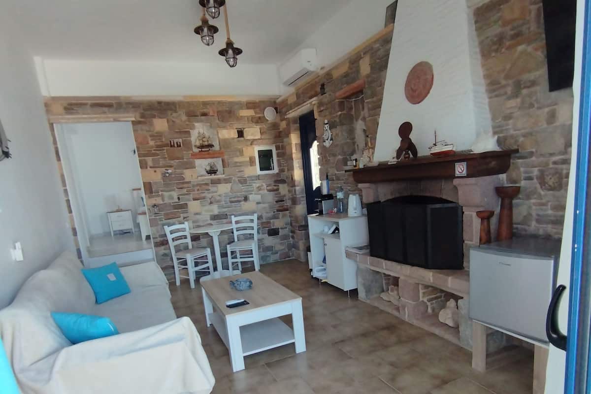 A living room with a stone wall, a fireplace, a sofa, and a coffee table.