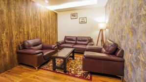 A living room with a brown leather sofa set, a glass coffee table, and a patterned rug. - Carom The Castle Resort Fagu Shimla (Theog)