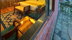 A modern bedroom with a large bed, a desk, and a chair. There is a window overlooking a balcony. - Carom The Castle Resort Fagu Shimla (Theog)