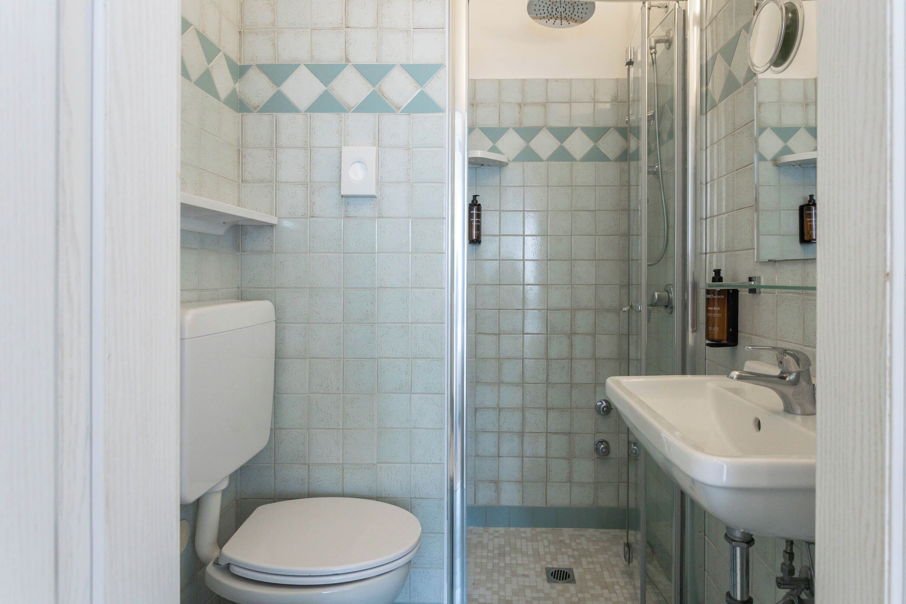 A bathroom with a toilet, shower, and sink.