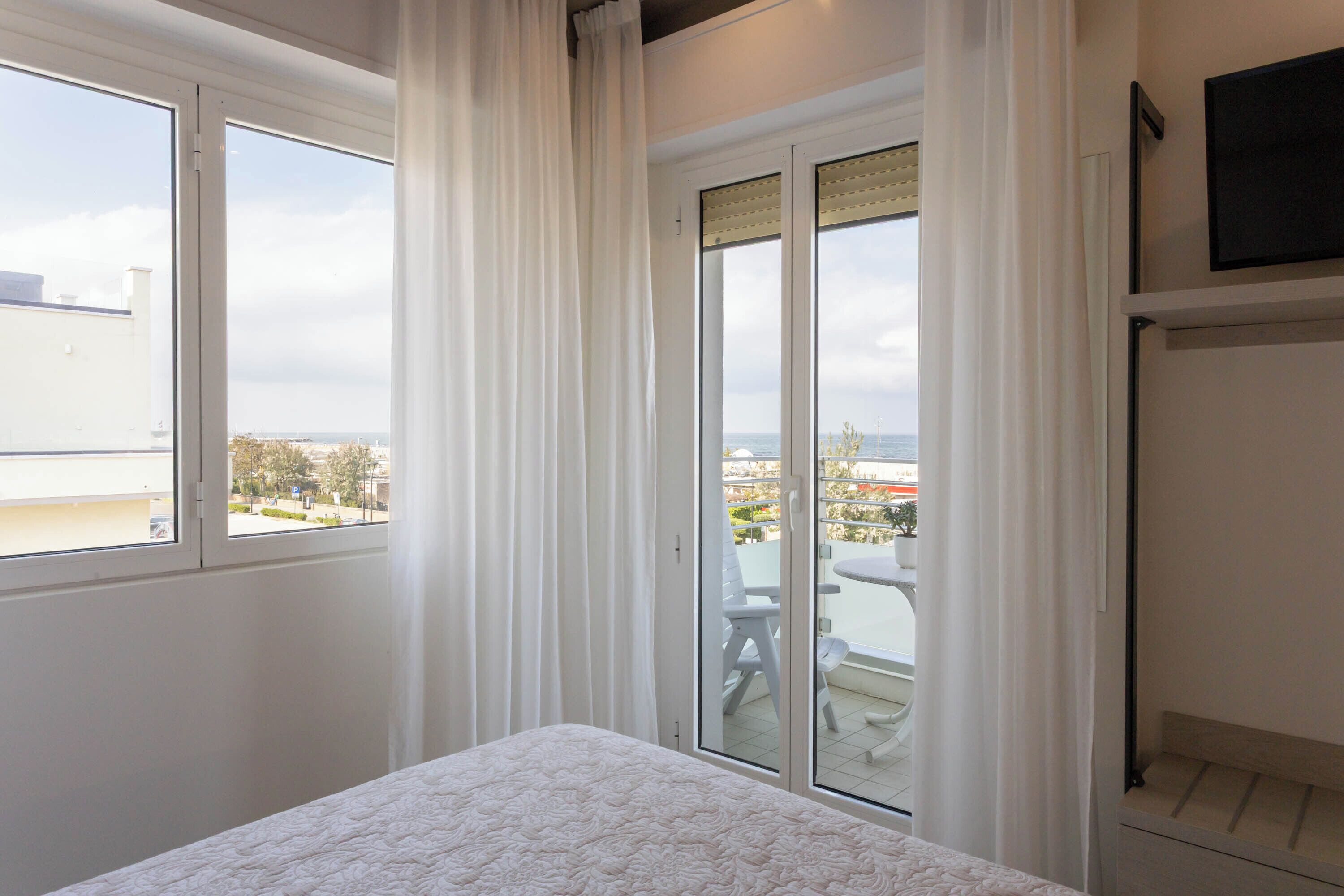 A bedroom with a bed, a window, and a view of the outside.