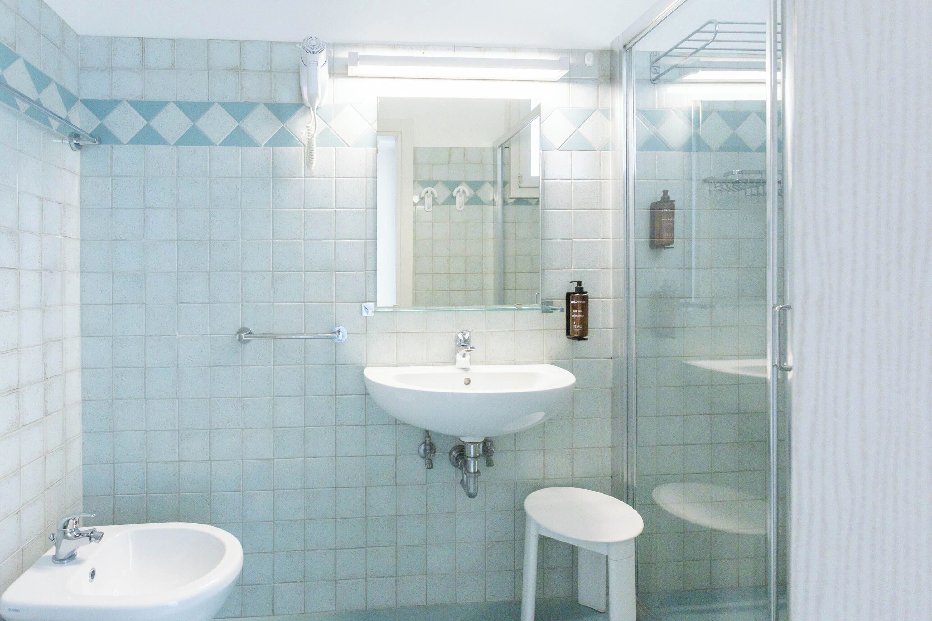 Baño con lavamanos, espejo y ducha.