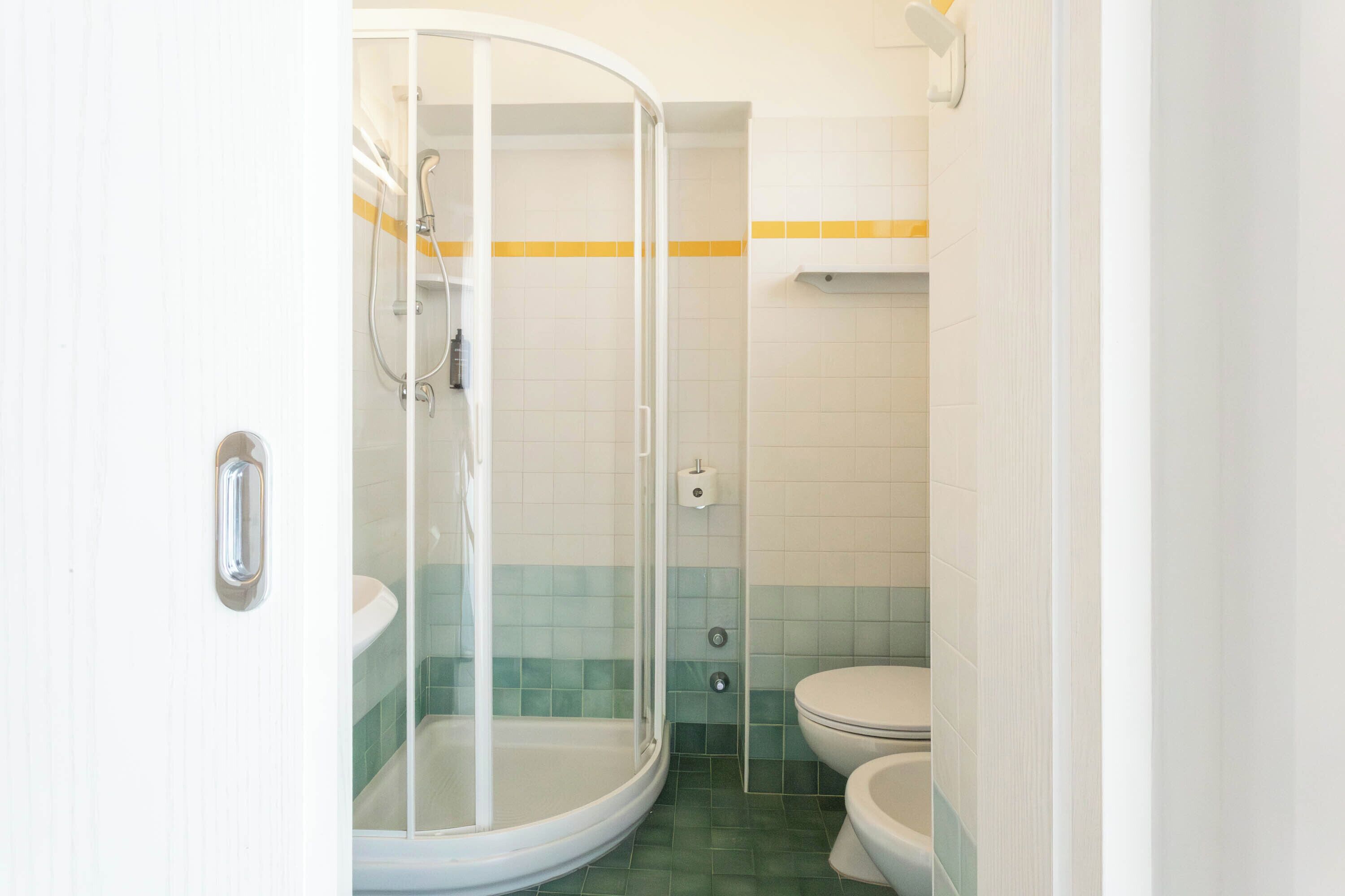 A bathroom with a glass-enclosed shower, a toilet, and a sink.