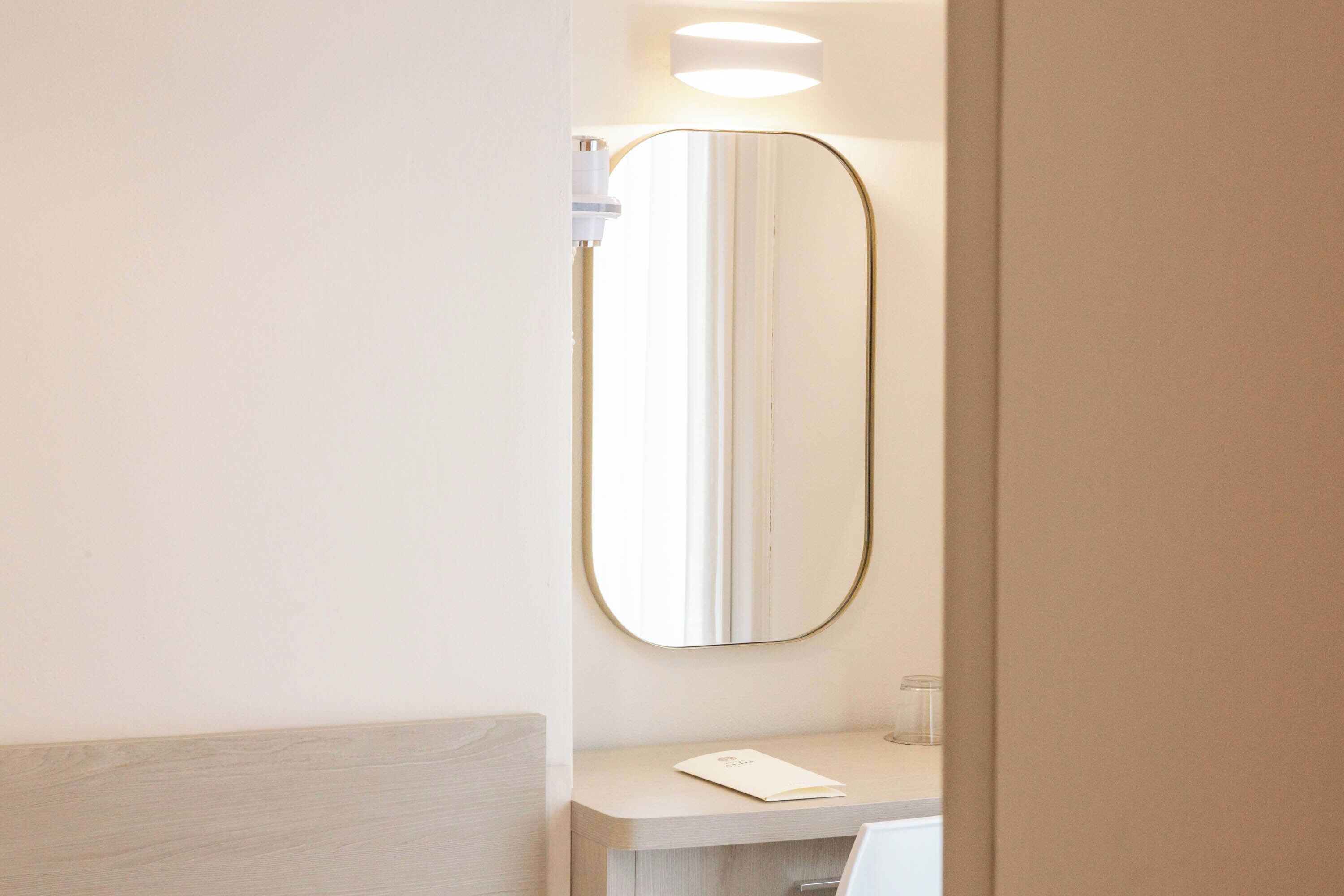 Ein Badezimmer mit Spiegel, einer Lampe und einer Arbeitsplatte.