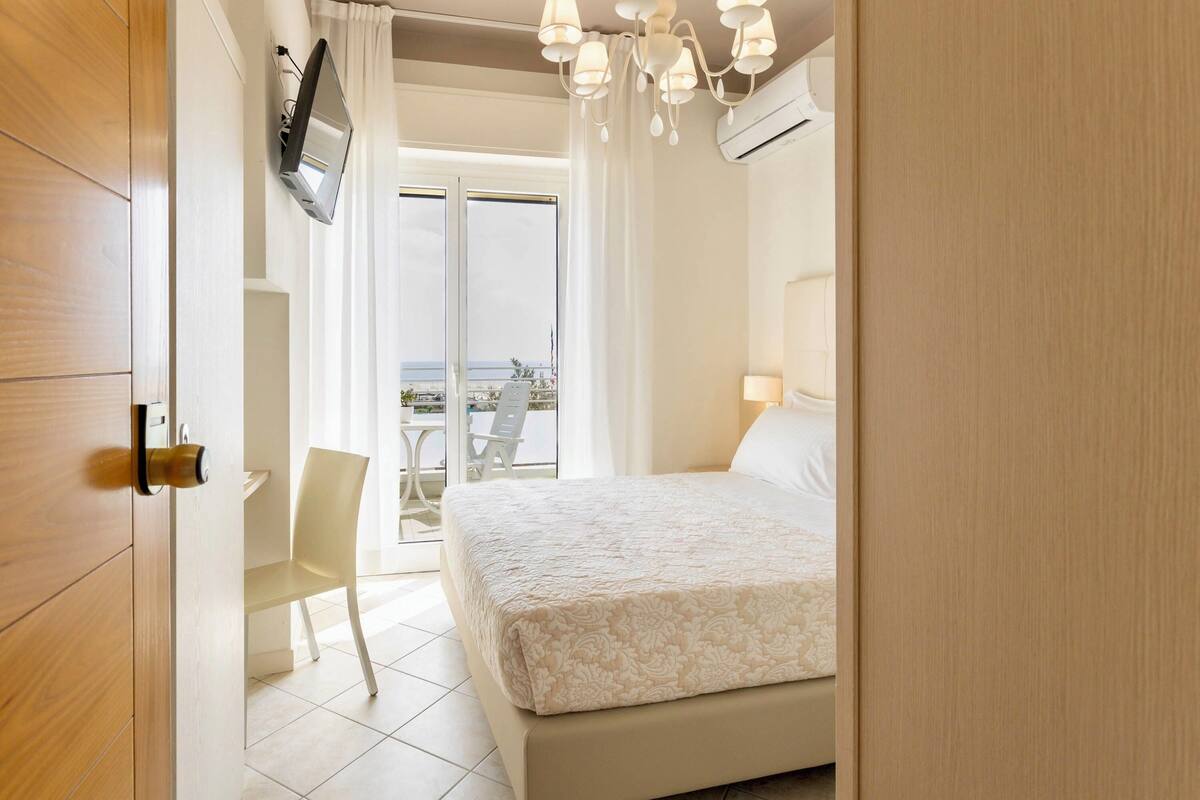 Un dormitorio con cama, una silla, un televisor y vistas al exterior.