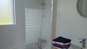 Un bagno moderno con cabina doccia in vetro, un mobile vanitario in legno con specchio e una finestra che offre luce naturale.