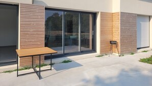 Un edificio moderno con un'ampia porta a vetri scorrevoli, una panca di legno e un tavolino.