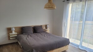 Camera da letto moderna con struttura letto in legno, testiera con mensole integrate e un'ampia finestra con tende leggere.