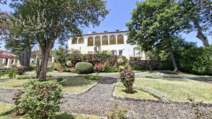 A building with a symmetrical facade, arched windows, and a stone pathway leading to the entrance. - Cozy Studio in a fabulous Quinta with pool and sea view! (Funchal)